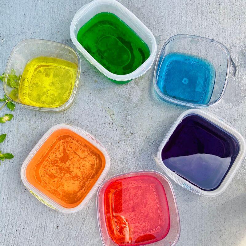 six containers of colored water in rainbow order