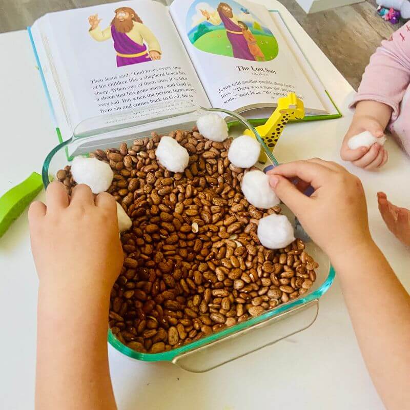 child playing with lost sheep sensory bin